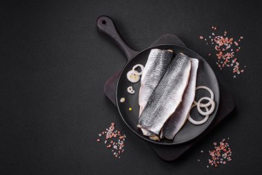 Lezzetli tuzlu ringa fileto yağlı siyah seramik tabakta koyu beton arka planda