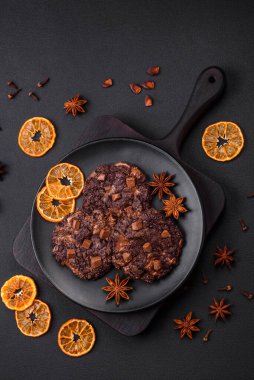 Lezzetli taze yulaf ezmesi yuvarlak kurabiyeler, siyah seramik tabakta çikolata, koyu beton arka planda.