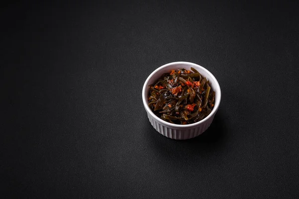 用红辣椒 香料和盐装饰在深色混凝土背景上的美味的腌制海藻 美味的素食沙拉 — 图库照片
