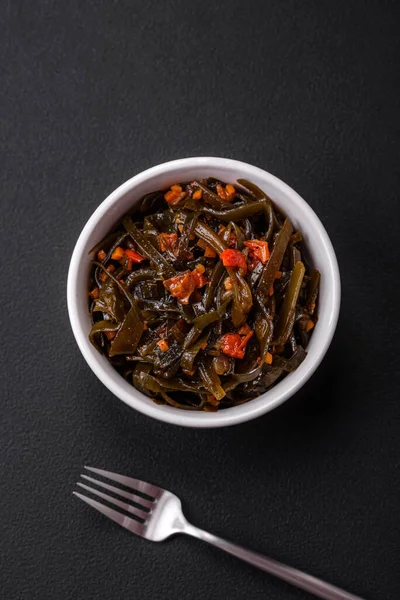 stock image Delicious marinated seaweed with paprika, spices and salt on a dark concrete background. Delicious vegetarian salad