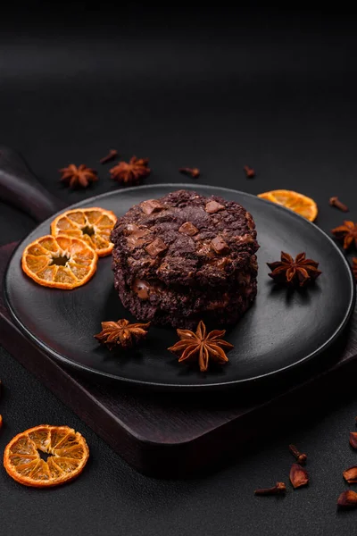 stock image Delicious fresh oatmeal round cookies with chocolate on a black ceramic plate on a dark concrete background