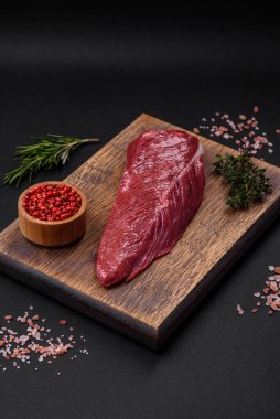 Koyu beton arka planda tahta bir kesme tahtasının üzerinde taze ve güzel bir parça et.