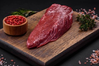 Koyu beton arka planda tahta bir kesme tahtasının üzerinde taze ve güzel bir parça et.