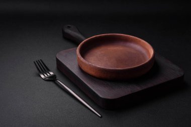 Koyu desenli beton arka planda boş kahverengi seramik plaka. Mutfak aletleri