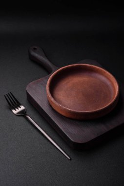 Koyu desenli beton arka planda boş kahverengi seramik plaka. Mutfak aletleri