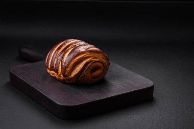 Lezzetli, çıtır çıtır, taze tarçınlı çörek, koyu beton arka planda.