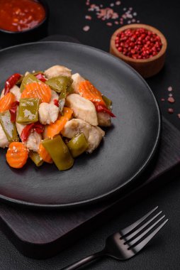 Lezzetli tavuk dilimleri ve buğulanmış sebzeler havuç, brokoli, kuşkonmaz fasulyesi ve biber koyu beton arka planda.