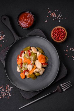 Lezzetli tavuk dilimleri ve buğulanmış sebzeler havuç, brokoli, kuşkonmaz fasulyesi ve biber koyu beton arka planda.