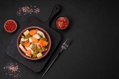 Lezzetli tavuk dilimleri ve buğulanmış sebzeler havuç, brokoli, kuşkonmaz fasulyesi ve biber koyu beton arka planda.