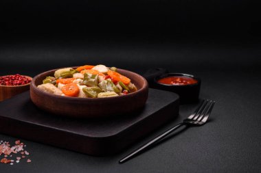 Lezzetli tavuk dilimleri ve buğulanmış sebzeler havuç, brokoli, kuşkonmaz fasulyesi ve biber koyu beton arka planda.