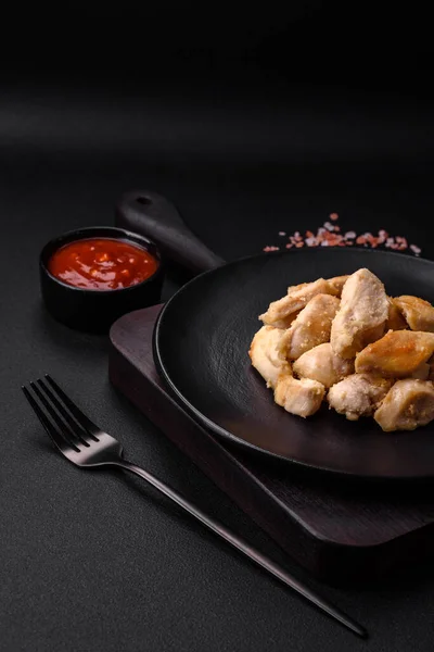 stock image Delicious chicken slices baked with spices and herbs on a round ceramic plate on a dark concrete background