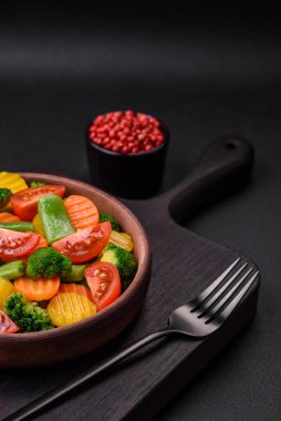 Taze ve buğulanmış sebze salatası kiraz domatesleri, brokoli, havuç ve kuşkonmaz fasulyeleri koyu beton arka planda.