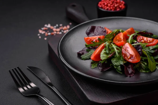 stock image Salad of fresh cherry tomatoes, arugula, spinach, young beet leaves and other greens on a dark concrete background