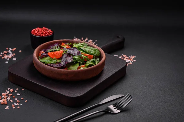 Stock image Salad of fresh cherry tomatoes, arugula, spinach, young beet leaves and other greens on a dark concrete background