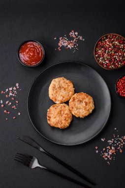 Lezzetli taze pirzola ya da baharatlı köfte, bitki ve domates soslu koyu beton arka planda.