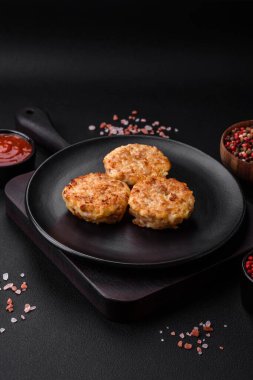 Lezzetli taze pirzola ya da baharatlı köfte, bitki ve domates soslu koyu beton arka planda.