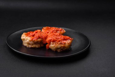 Lezzetli taze pirzola ya da baharatlı köfte, bitki ve domates soslu koyu beton arka planda.