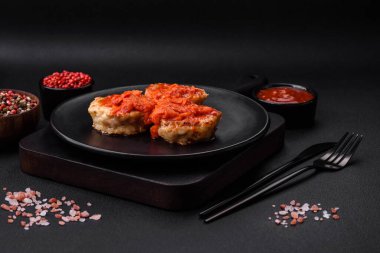 Lezzetli taze pirzola ya da baharatlı köfte, bitki ve domates soslu koyu beton arka planda.