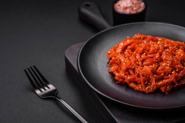 Kurutulmuş mürekkep balığı dilimlenmiş ve koyu beton arka planda susam tohumu ve baharatla tatlandırılmış. Kore mutfağı.