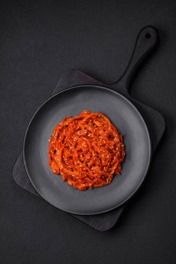 Kurutulmuş mürekkep balığı dilimlenmiş ve koyu beton arka planda susam tohumu ve baharatla tatlandırılmış. Kore mutfağı.