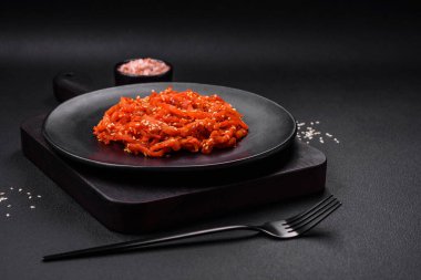 Kurutulmuş mürekkep balığı dilimlenmiş ve koyu beton arka planda susam tohumu ve baharatla tatlandırılmış. Kore mutfağı.