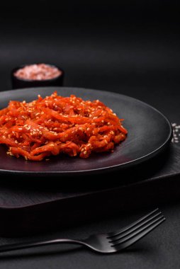 Kurutulmuş mürekkep balığı dilimlenmiş ve koyu beton arka planda susam tohumu ve baharatla tatlandırılmış. Kore mutfağı.