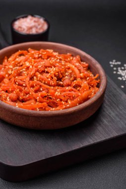 Kurutulmuş mürekkep balığı dilimlenmiş ve koyu beton arka planda susam tohumu ve baharatla tatlandırılmış. Kore mutfağı.