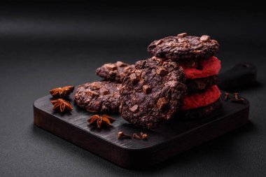 Koyu beton arka planda siyah seramik tabakta çikolatalı ve fındıklı lezzetli çıtır yulaf ezmeli kurabiyeler.