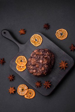 Koyu beton arka planda siyah seramik tabakta çikolatalı ve fındıklı lezzetli çıtır yulaf ezmeli kurabiyeler.