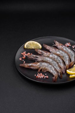 Ahşap kesme tahtasına baharat ve tuz sürülmüş kaplan karidesi veya langoustine koyu beton arka planda