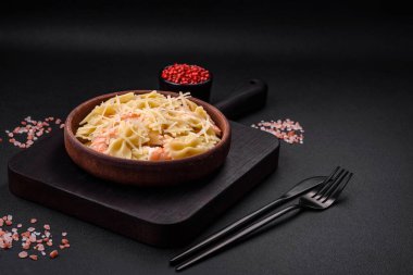 Lagoustine karidesli nefis farfalle makarna krem soslu ve peynirli koyu beton arka planda.