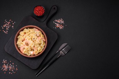 Lagoustine karidesli nefis farfalle makarna krem soslu ve peynirli koyu beton arka planda.