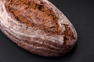 Koyu beton arka planda tahıllı lezzetli kahverengi ekşi ekmek.