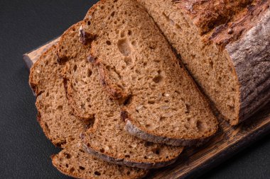 Koyu beton arka planda tahıllı lezzetli kahverengi ekşi ekmek.