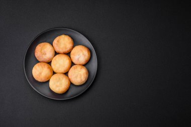 Kuru üzümlü ve vanilyalı lezzetli süzme peynirli kekler. Siyah seramik tabakta, koyu beton arka planda.