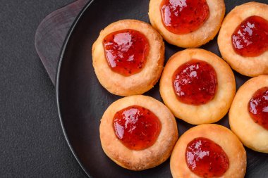 Kuru üzümlü ve vanilyalı lezzetli süzme peynirli kekler. Siyah seramik tabakta, koyu beton arka planda.