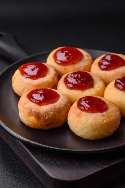 Kuru üzümlü ve vanilyalı lezzetli süzme peynirli kekler. Siyah seramik tabakta, koyu beton arka planda.