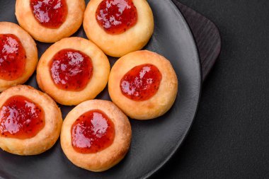 Kuru üzümlü ve vanilyalı lezzetli süzme peynirli kekler. Siyah seramik tabakta, koyu beton arka planda.