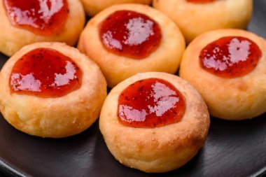 Kuru üzümlü ve vanilyalı lezzetli süzme peynirli kekler. Siyah seramik tabakta, koyu beton arka planda.