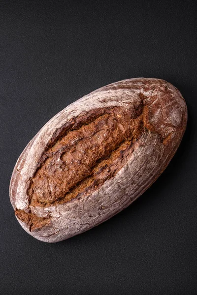 濃いコンクリートの背景に穀物とおいしい新鮮な茶色の生地のパン — ストック写真