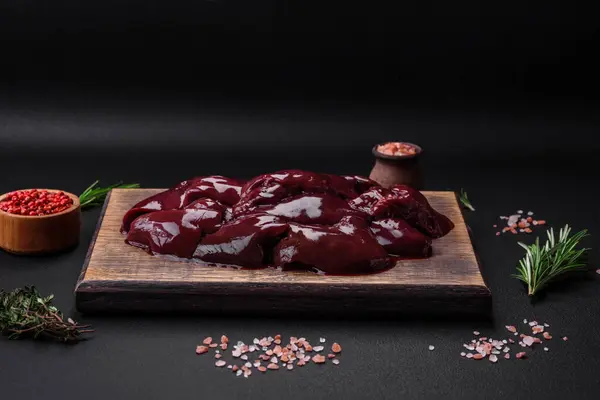 stock image Fresh raw chicken, turkey or duck liver with salt, spices and herbs on a dark concrete background