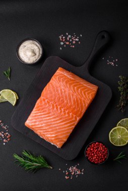 Koyu beton arka planda baharat ve bitkilerle taze çiğ balık filetosu.