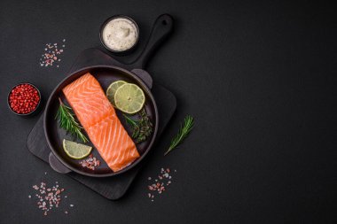 Koyu beton arka planda baharat ve bitkilerle taze çiğ balık filetosu.