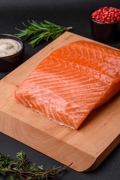 stock image Fresh tasty raw red fish fillet with spices and herbs on a dark concrete background