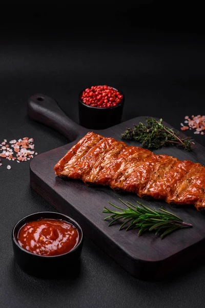 stock image Delicious fresh grilled or smoked ribs with salt, spices and herbs on dark concrete background