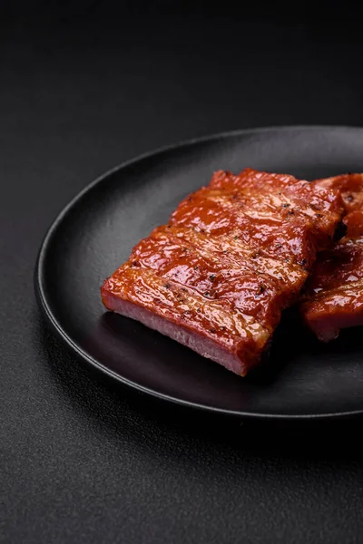 stock image Delicious fresh grilled or smoked ribs with salt, spices and herbs on dark concrete background