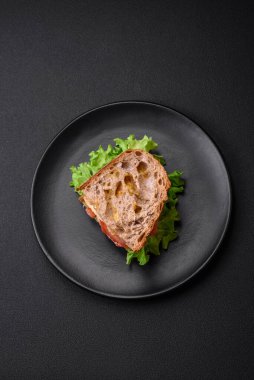 Lezzetli sandviç, kızarmış ekmek, tavuk, domates ve marul, koyu beton arka planda.