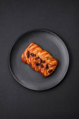 Koyu beton arka planda fındık ve şuruplu lezzetli fırında pişmiş at kuyruğu çöreği.