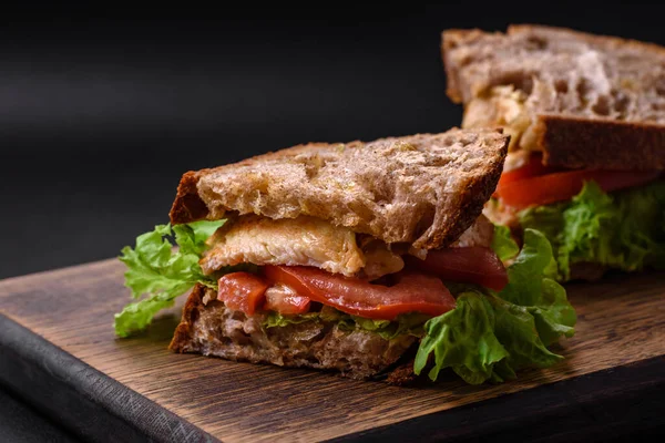 어두운 배경에 토스트 닭고기 도마도 상추가 맛있는 샌드위치 — 스톡 사진