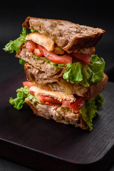 어두운 배경에 토스트 닭고기 도마도 상추가 맛있는 샌드위치 — 스톡 사진
